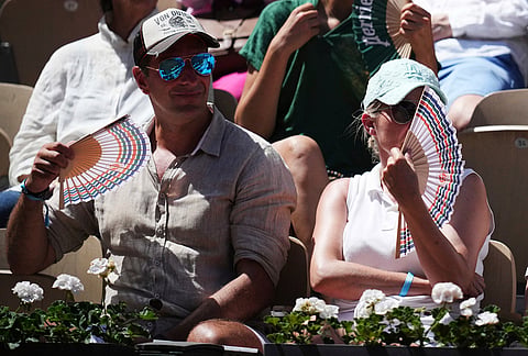 Spectators cool themselves with hand fans during the first round women's singles tennis match between Elina Svitolina of Ukraine and Anna Bondar of Hungary at the French Open tennis tournament in Paris.