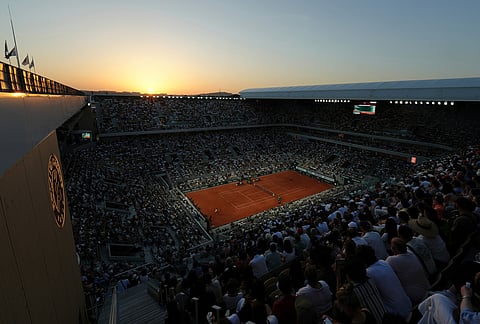 The sun sets over the center court Philippe Chatrier as Hugo Gaston of France, left, plays against Gael Monfils of France during their first round men's singles tennis match at the French Open tennis tournament in Paris.