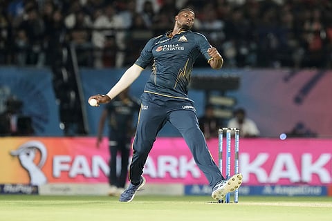 Gujarat Titans' Jason Holder bowls a delivery during the Indian Premier League cricket match between Gujarat Titans and Royal Challengers Bengaluru in Dharamshala, India.
