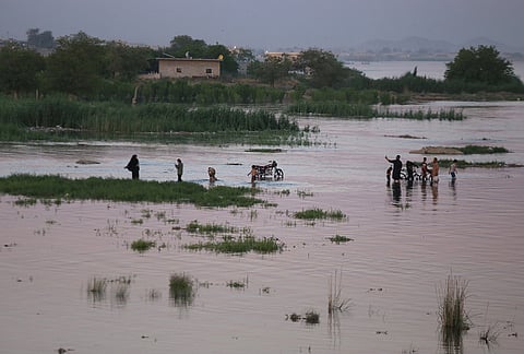 Residents wade through floodwaters along the banks of the Euphrates River near Raqqa, northeastern Syria.