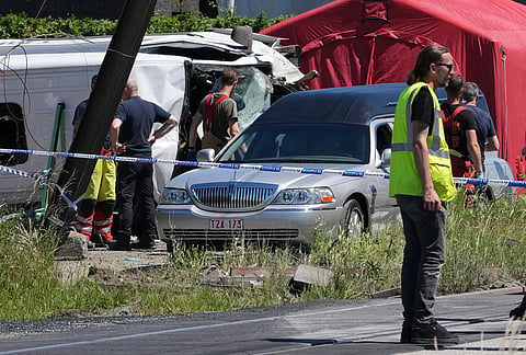 A hearse drives away at a level crossing where a train collided with a school van in Buggenhout, Belgium.