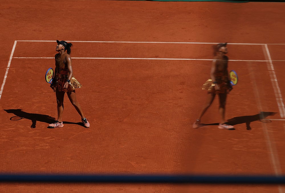 Naomi Osaka of Japan reflects in a glass as she reacts during the first round womens singles tennis match against Laura Siegemund of Germany at the French Open tennis tournament in Paris.
