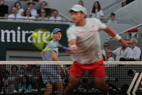 Jannik Sinner of Italy, left, looks as Clement Tabur of France returns during their first round men's singles tennis match at the French Open tennis tournament in Paris.