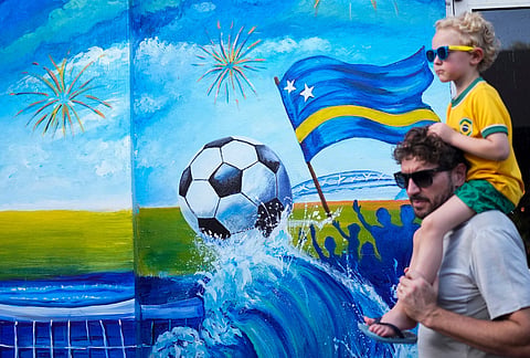 Tourists walk past a mural celebrating Curacao's qualification for the FIFA World Cup in Willemstad, Curacao.