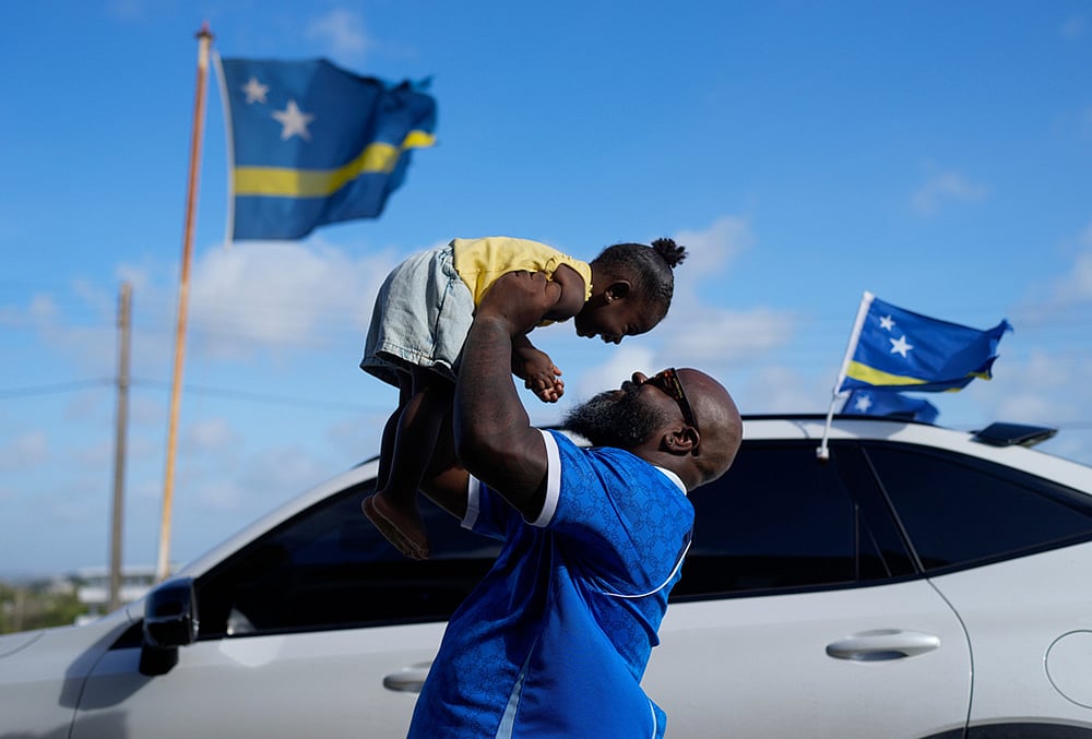 Brenton Balentien, known as Blue Face, a leader of soccer fans of Curacaos national soccer team, holds up his daughter in Willemstad, Curacao.