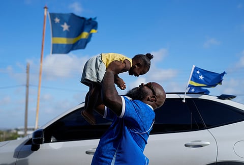 Brenton Balentien, known as Blue Face, a leader of soccer fans of Curacao's national soccer team, holds up his daughter in Willemstad, Curacao.