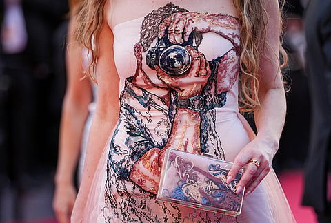 A woman wearing a dress embroidered with a depiction of a photographer walks on the red carpet at the opening ceremony and premiere of the film 'The Electric Kiss' during 79th international film festival, Cannes, southern France.