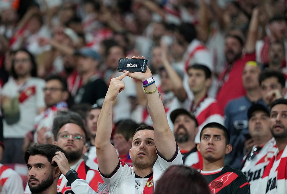 A fan of Rayo uses his phone to call for a doctor to come to the stands during the Europa Conference League final soccer match between Crystal Palace and Rayo Vallecano in Leipzig, Germany.