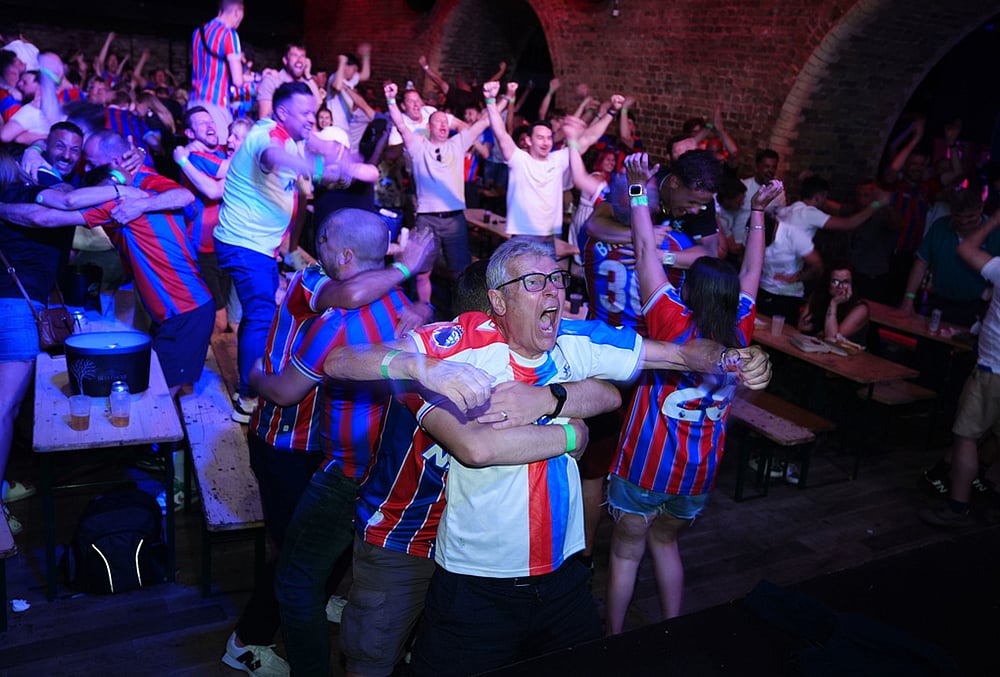 Crystal Palace fans celebrate after their team scored a goal as they watch a screening of the Europa Conference League final soccer match between Crystal Palace and Rayo Vallecano in London. 
