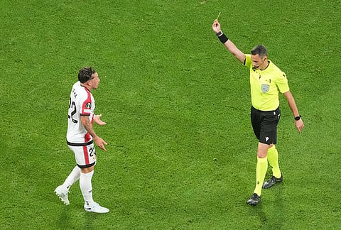 Referee Maurizio Mariani shows a yellow card to Rayo's Alfonso Espino during the Europa Conference League final soccer match between Crystal Palace and Rayo Vallecano in Leipzig, Germany.