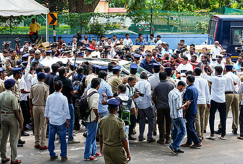 Security personnel and media gather outside Karnataka Chief Minister Siddaramaiah's residence amid heightened activity following reports about his announcement to step down, in Bengaluru.