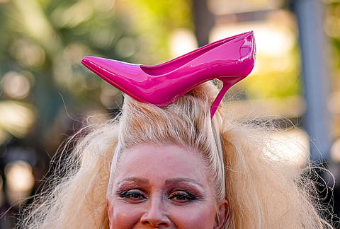 Elena Lenina smiles as she walks on the red carpet with a shoe in her hair at the premiere of the film 'Karma' at the 79th international film festival, Cannes, southern France.
