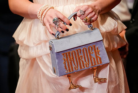 A woman holds a purse decorated with water bird legs that reads "Love" upon arrival at the premiere of the film 'The Man I Love' at the 79th international film festival, Cannes, southern France.