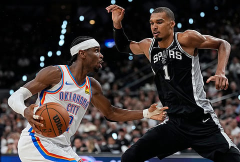 Oklahoma City Thunder guard Shai Gilgeous-Alexander (2) drives against San Antonio Spurs forward Victor Wembanyama (1) in the second half of Game 6 in the Western Conference finals NBA basketball playoffs series, in San Antonio. 