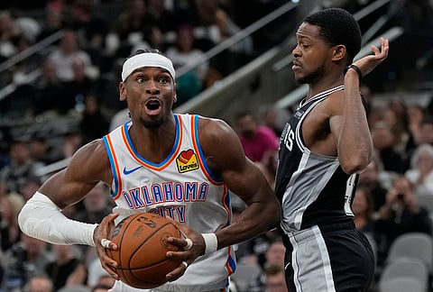 Oklahoma City Thunder guard Shai Gilgeous-Alexander (2) moves on San Antonio Spurs guard De'aaron Fox (4) in the second half of Game 6 in the Western Conference finals NBA basketball playoffs series, in San Antonio.