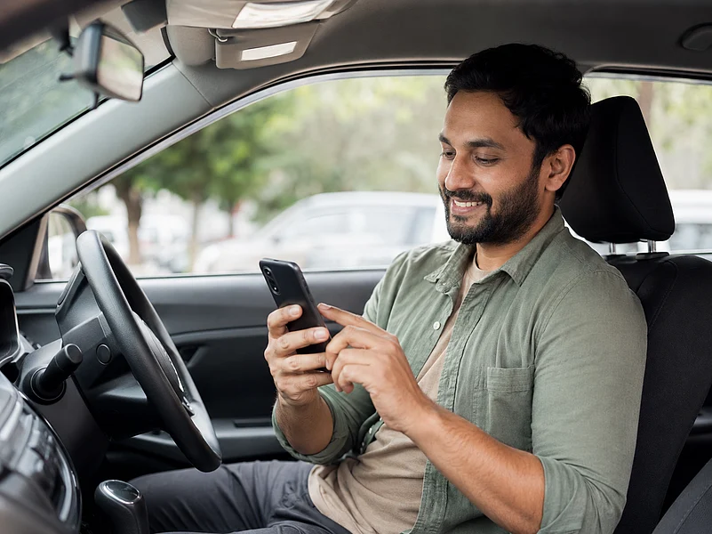 A man sitting in a car using his phone