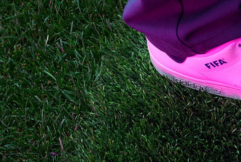 The shoe of Ewen Hodge, head of pitch infrastructure with FIFA, is seen near the threshold between grass and artificial turf during a preview of the grass installed at Dallas Stadium, ahead of the 2026 FIFA World Cup soccer tournament. 