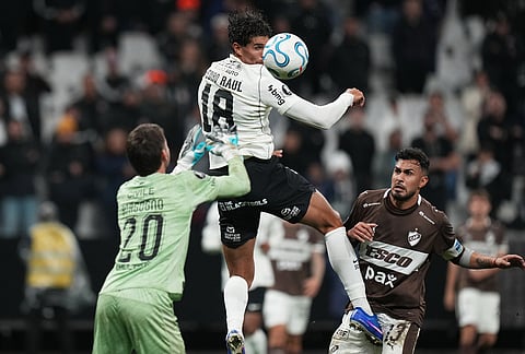 Pedro Raul of Brazil's Corinthians, center, heads the ball as he is challenged by goalkeeper Matias Borgogno of Argentina's Platense, left, during a Copa Libertadores Group E soccer match in Sao Paulo.
