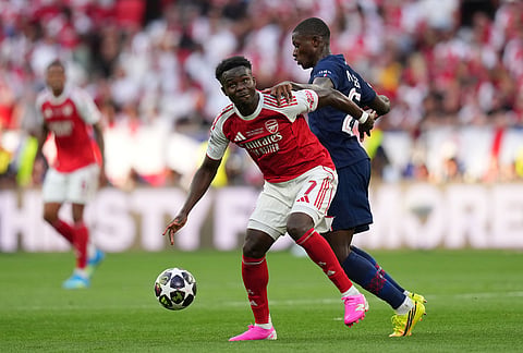 Arsenal's Bukayo Saka, foreground, challenges for the ball with PSG's Nuno Mendes during the Champions League final soccer match between Paris Saint-Germain and Arsenal in Budapest, Hungary.