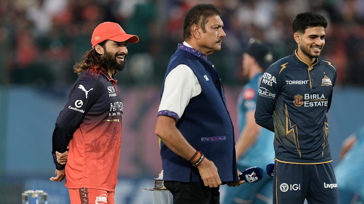 Royal Challengers Bengaluru’s captain Rajat Patidar, left, Gujarat Titans’ captain Shubman Gill, right, and commentator Ravi Shastri wait for the coin toss ahead of the Indian Premier League cricket match between Gujarat Titans and Royal Challengers Bengaluru in Dharamshala, India, Tuesday, May 26, 2026.  - | Photo: AP/Ashwini Bhatia