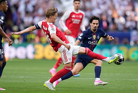 Arsenal's Martin Odegaard reaches for the ball in front of PSG's Vitinha, right, during the Champions League final soccer match between Paris Saint-Germain and Arsenal in Budapest, Hungary.