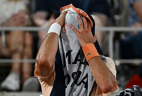 Novak Djokovic of Serbia covers by a towel during a break of the first round men's singles tennis match against Giovanni Mpetshi Perricard of France at the French Open tennis tournament in Paris.