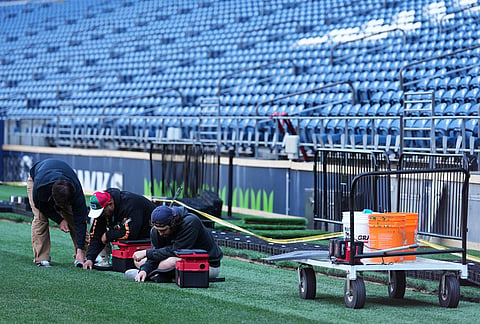 Workers remove rubber pellets at the edge of the hybrid natural grass field as preparations continue at Seattle Stadium, normally known as Lumen Field, ahead of the 2026 FIFA World Cup matches, in Seattle.
