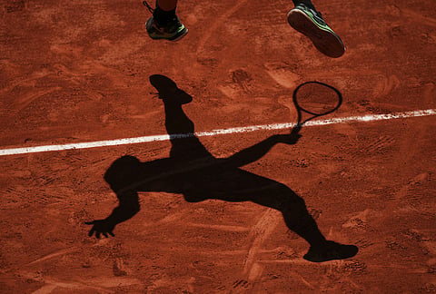 Camilo Ugo Carabelli of Argentina casts a shadow as he serves to Andrey Rublev of Russia during their second round men's singles tennis match at the French Open tennis tournament in Paris.