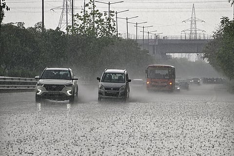 Vehicles move on a road amid rainfall, in Noida.