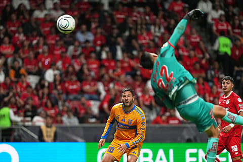 Tigres' Andre Pierre Gignac, center, looks as Toluca's goalkeeper Luis Garcia makes a save during the CONCACAF Champions Cup final soccer match in Toluca, Mexico.