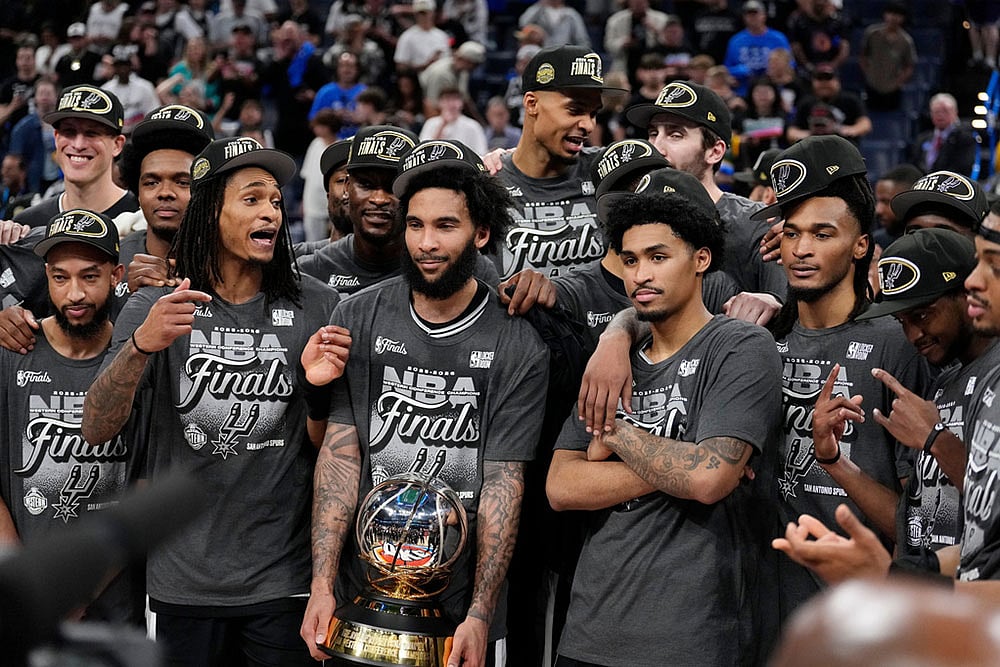 San Antonio Spurs' Jordan McLaughlin, left, Devin Vassell, second from left, Julian Champagnie, center, Dylan Harper, second from right, and Stephon Castle, right, celebrate after Game 7 of the Western Conference finals of the NBA basketball playoffs series win against the Oklahoma City Thunder in Oklahoma City. - | Photo: AP/Tony Gutierrez