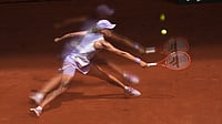 (AP Photo/Christophe Ena) : Iga Swiatek of Poland is reflected in a glass as she returns to Magda Linette of Poland during their third round women's singles tennis match at the French Open tennis tournament in Paris, Friday, May 29, 2026.