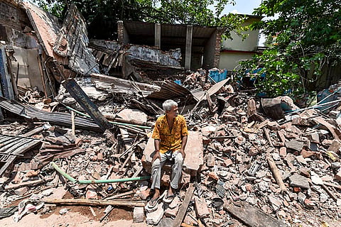 A man sits amid debris after an anti-encroachment drive, near Dum Dum Junction station in Kolkata.