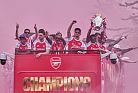 | Photo: AP/Kin Cheung : Arsenal's Bukayo Saka, right, lifts the trophy during a parade for winning the English Premier League title, in London.