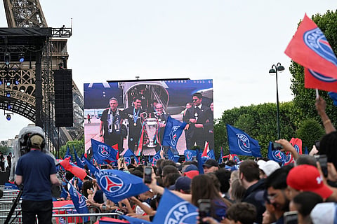Fans cheer as a giant monitor shows PSG's head coach Luis Enrique and team upon landing, during celebrations the day after winning the Champions League title, at the Eiffel Tower, in Paris.