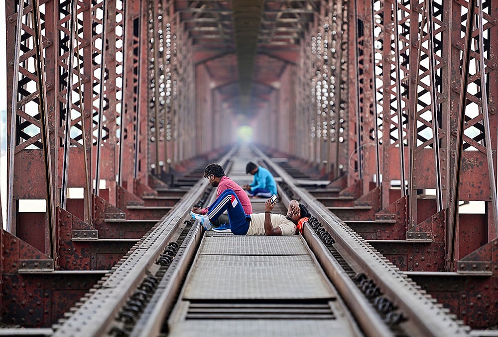 Prayagraj: People rest on the railway track of the Lord Curzon Bridge over River Ganga on a hot summer day, in Prayagraj. - | Photo: PTI 