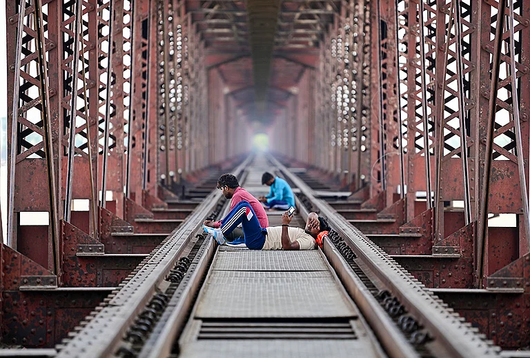 Prayagraj: People rest on the railway track of the Lord Curzon Bridge over River Ganga on a hot summer day, in Prayagraj. - | Photo: PTI