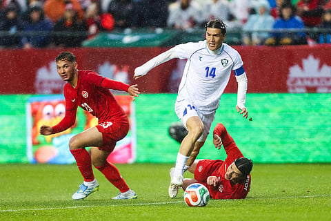 Uzbekistan's Eldor Shomurodov (14) fends off Canada's Niko Sigur (23) and Alistair Johnston, bottom right, during the second half of an international friendly soccer match in Edmonton, Alberta.