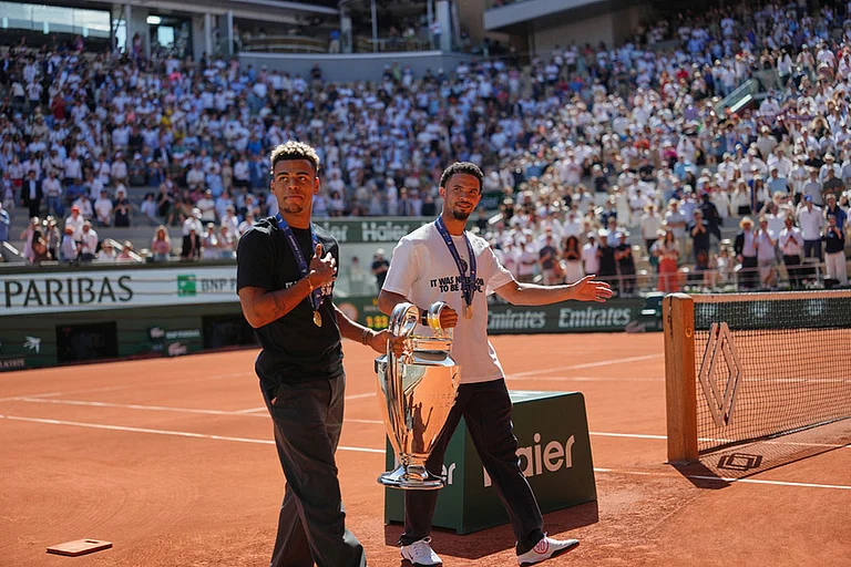 PSG's Desire Doue, left, and Warren Zaire-Emery walk onto the center court with Chgampions league trophy at the French Open tennis tournament in Paris. - | Photo: AP/Aurelien Morissard