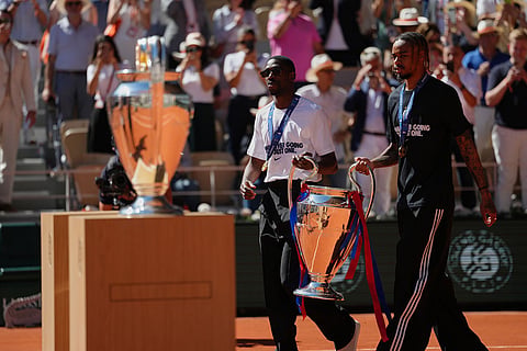 PSG's Ousmane Dembele, left, and Bradley Barcola walk onto the court with the Champions League trophy during the French Open in Paris.