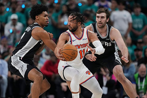 New York Knicks guard Jalen Brunson (11) spins as San Antonio Spurs guard Dylan Harper, left, defends during the first half of Game 1 of the NBA Finals basketball series, in San Antonio.
