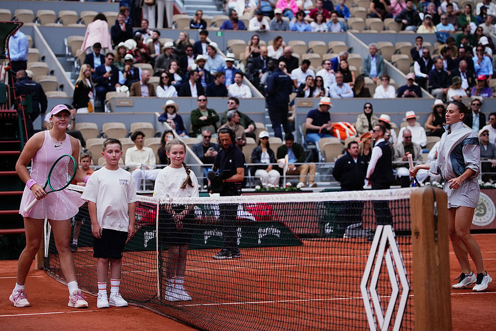 Russia's Mirra Andreeva poses with children while Ukraine's Marta Kostyuk refused during teh senifinal tennis tennis match at the French Open in Paris. - | Photo: AP/Christophe Ena