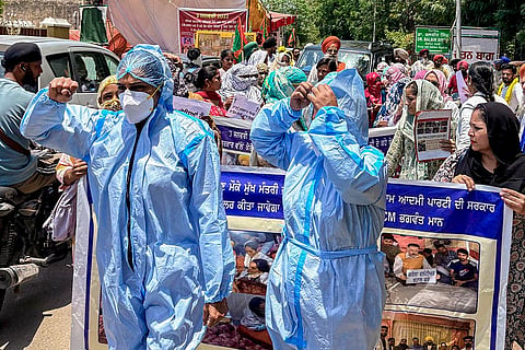 People dressed as Covid-19 medical staff stage a protest near the residence of Punjab health and family minister Dr Balbir Singh demanding to fulfill government promises of regular employment and calling for recognition of their services rendered during the COVID-19 pandemic.