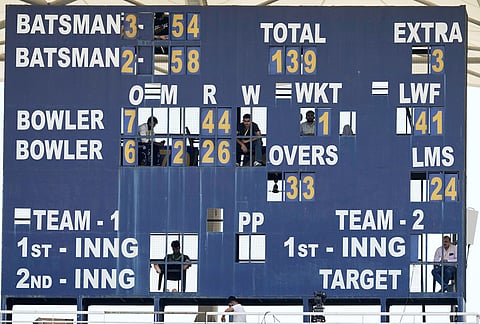 Scorekeepers keep an eye on the play from behind an analog scoreboard on day one of the cricket test match between Afghanistan and India in New Chandigarh.