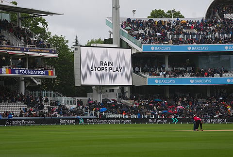 Spectators wait in the stands after rain stopped play during the third day of the Test match between England and New Zealand at Lord's cricket ground in London.