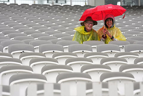 People shelter under umbrellas as rain stops play during the first day of the test match between England and New Zealand at Lord's cricket ground in London.