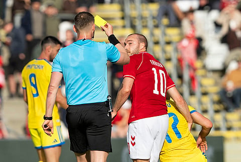 Denmark's Christian Eriksen is issued a yellow card from referee Sigurd Kringstad during an international football match with Ukraine, in Odense, Denmark.