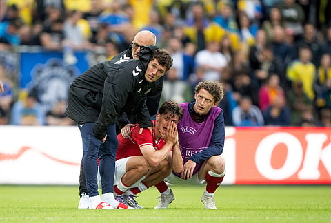 Denmark's Joakim Maehle, Andreas Christensen, and Jens Stage react after Christian Eriksen collapsed on the field during the international friendly soccer match between Denmark and Ukraine in Odense, Denmark.