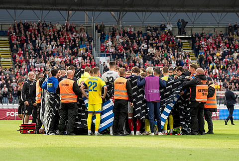 Players from Denmark and Ukraine form a circle around Denmark's player Christian Eriksen after he collapsed during the international friendly soccer match between Denmark and Ukraine in Odense, Denmark.