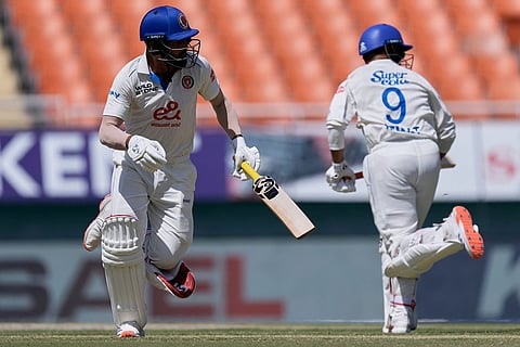 Afghanistan's Afsar Zazai, left, and batting partner Azmatullah Omarzai run between the wickets on day three of the cricket test match between Afghanistan and India in New Chandigarh, India.